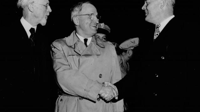 Presidentti George Albert Smith seisomassa erästä toista miestä kättelevän presidentti Harry S. Trumanin vieressä.
