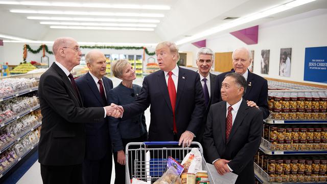 Yhdysvaltain presidentti Donald J. Trump kättelemässä presidentti Henry B. Eyringia kirkon ensimmäisestä presidenttikunnasta 4. joulukuuta 2017. Kuvassa myös, vasemmalta oikealle: Presidentti Russell M. Nelson kahdentoista apostolin koorumista; sisar Jean B. Bingham, Apuyhdistyksen ylijohtaja; piispa Gérald Caussé johtavasta piispakunnasta; Yhdysvaltain senaattori Orrin Hatch Utahista sekä Joel Moriyama, huoltotyöaukion johtaja. 
