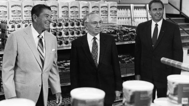 Vanhin Thomas S. Monson kahdentoista apostolin koorumista ja presidentti Gordon B. Hinckley, neuvonantaja ensimmäisessä presidenttikunnassa, yhdessä Yhdysvaltain presidentin Ronald Reaganin kanssa Ogdenin säilyketehtaassa erityisellä kiertokäynnillä huoltotyötiloissa vuonna 1982. 