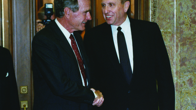 Presidentti Thomas S. Monson, neuvonantaja ensimmäisessä presidenttikunnassa, kättelemässä Yhdysvaltain presidentin George H. W. Bushin kanssa kirkon hallintorakennuksessa 17. heinäkuuta 1992. 